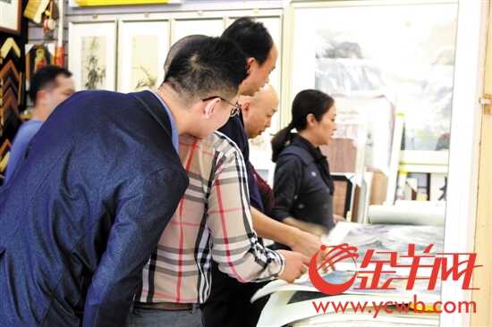 在文德路字画街一店铺内,正有顾客在购买画作 在文德路字画街一店铺内,正有顾客在购买画作