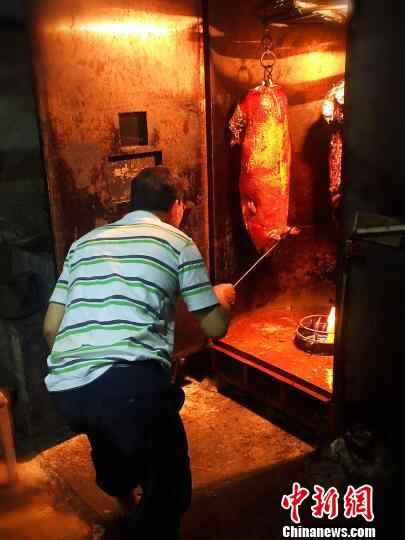 黄长达查看第三次焗皮中的烧猪 李晓春 摄