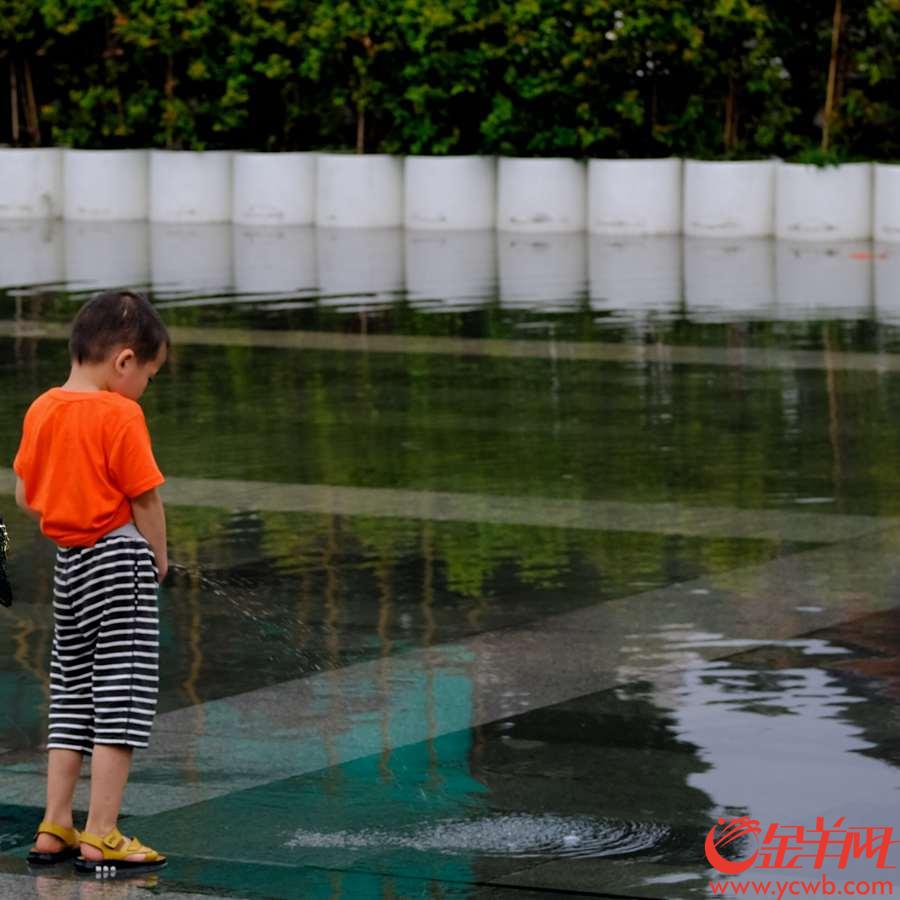 受台风影响，广州今日下午阵雨，给连续酷热的广州“降降温”，陈家祠广场一摊积水备受“欢迎”，孩子、街坊开心玩水。金羊网记者 陈秋明 摄影报道