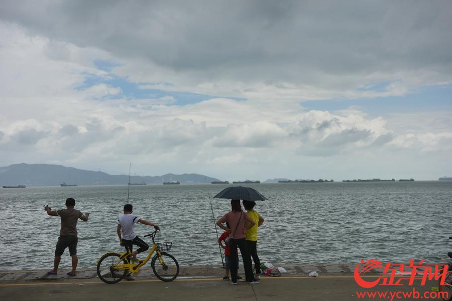 台风让深圳湾的天空变幻莫测，有市民在岸边钓鱼。王磊 摄
