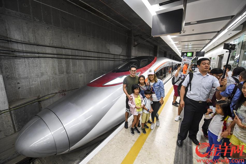 2018年9月23日，广深港高铁香港段，由香港西九龙站首发前往深圳北站的G5736列车准备开出。登车前，乘坐首班车的旅客和“动感号”列车合影留念。 记者 宋金峪 摄 