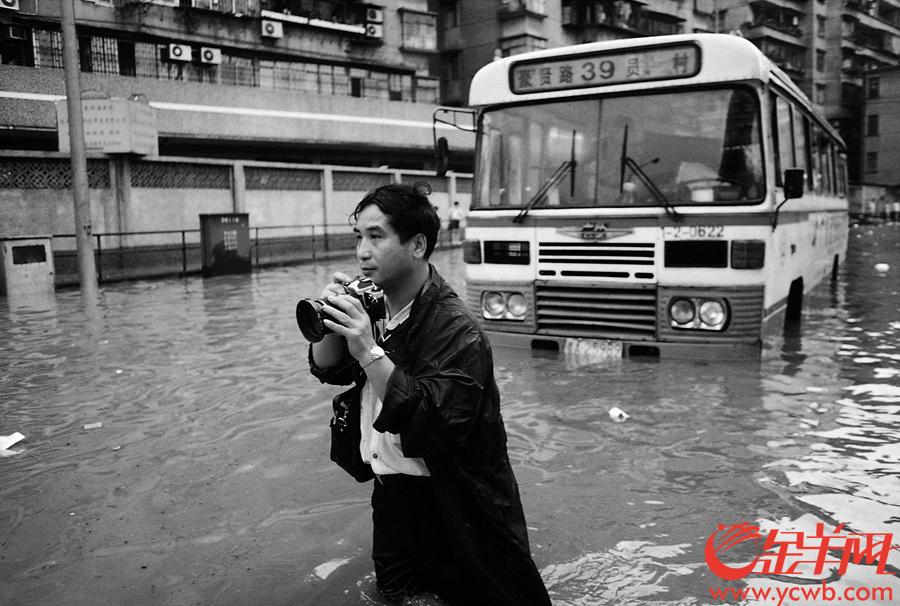 90年代，叶健强端着相机在广州水浸街现场拍摄。金羊网记者 陈秋明 摄