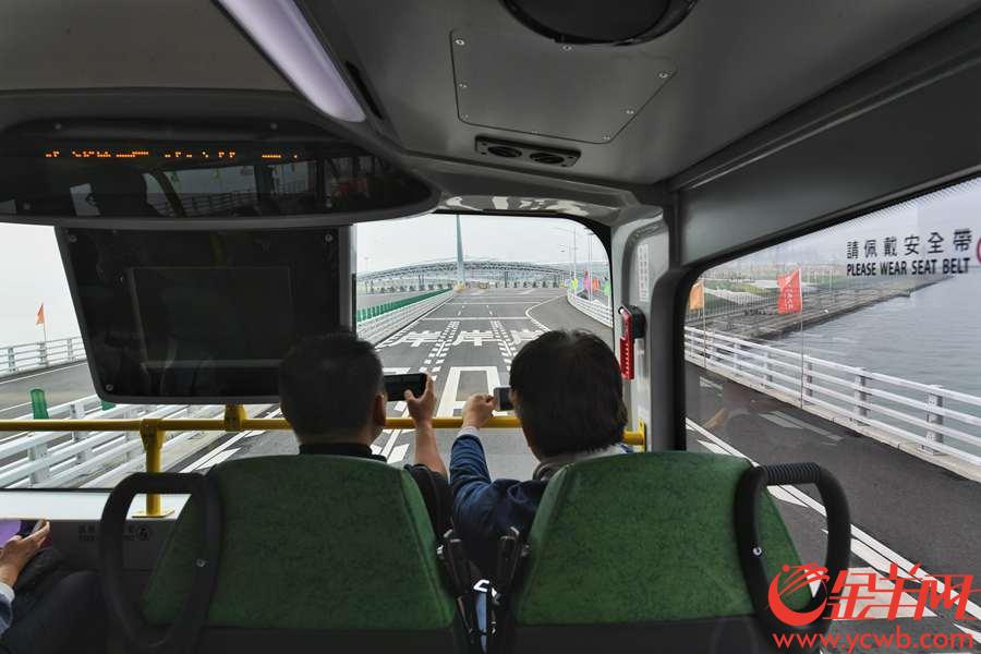 2018年10月24日，港珠澳大桥通车首日，旅客透过透过穿梭巴士玻璃向外拍照。 金羊网记者 汤铭明 摄