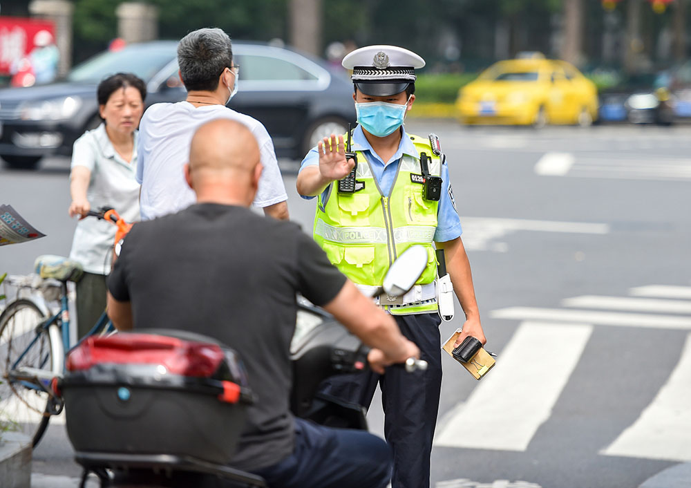 交警正在对骑乘电动自行车不佩戴头盔的违法行为进行现场处罚