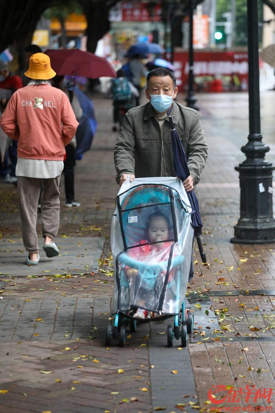 11月22日，广州市区受冷空气影响降雨降温，小朋友出门被家长“加罩”挡雨保温 羊城晚报全媒体记者 梁怿韬 摄