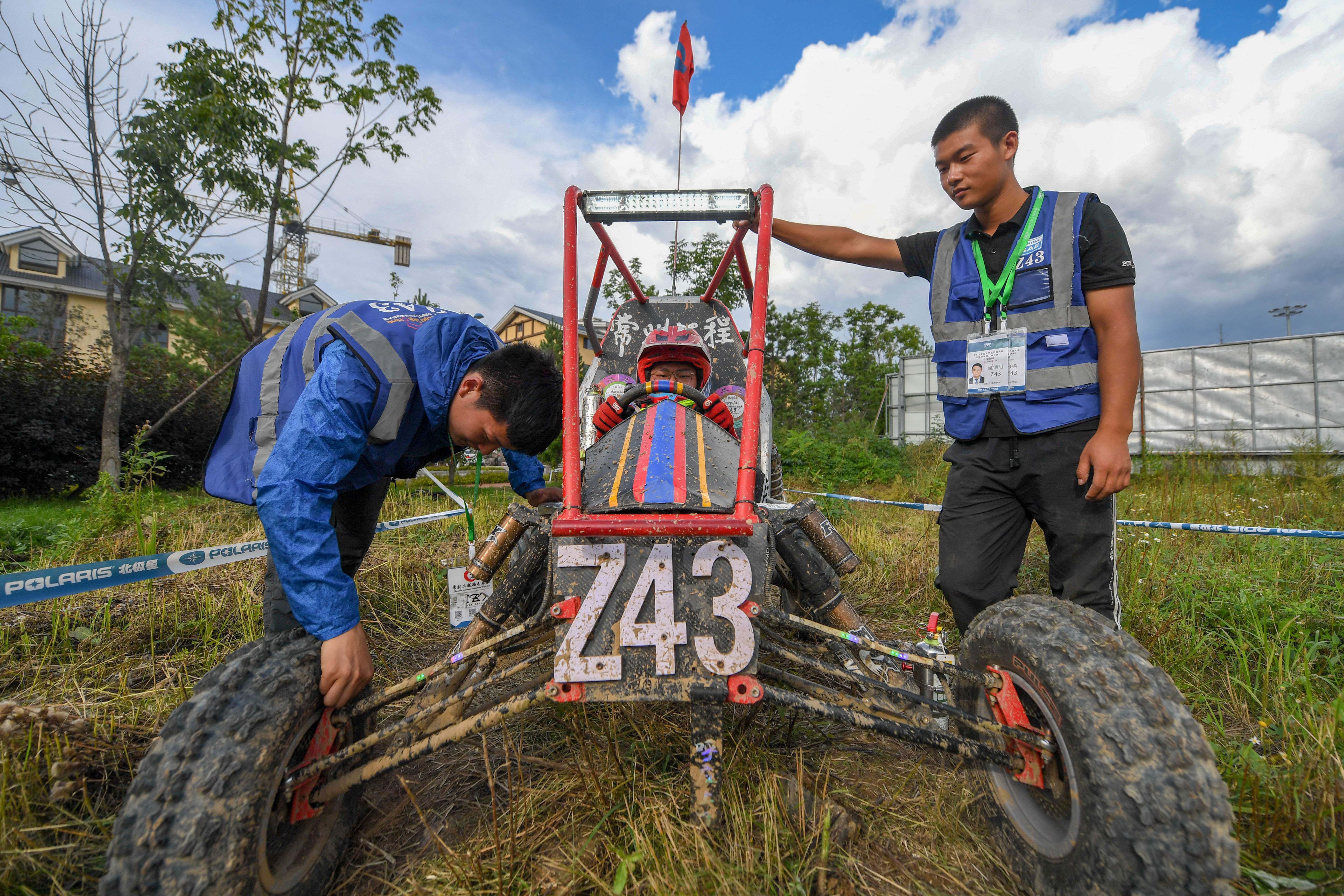 的大學生圍著一輛越野賽車緊張地忙碌著,為一項叫