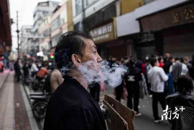 一名制衣厂老板边招工边抽着烟。